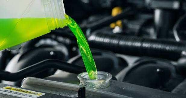 Mechanic pouring green coolant for a cooling system flush